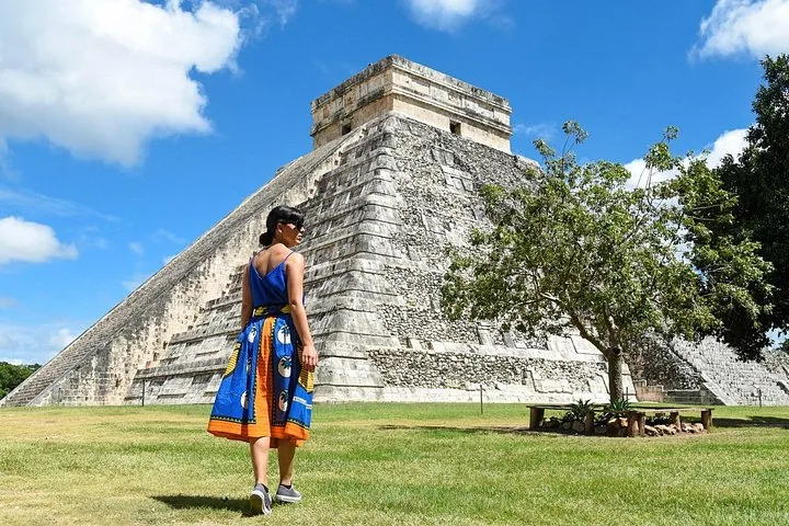 Eine Frau in einem blauen Rock geht auf El Castillo in Chichén Itzá zu.
