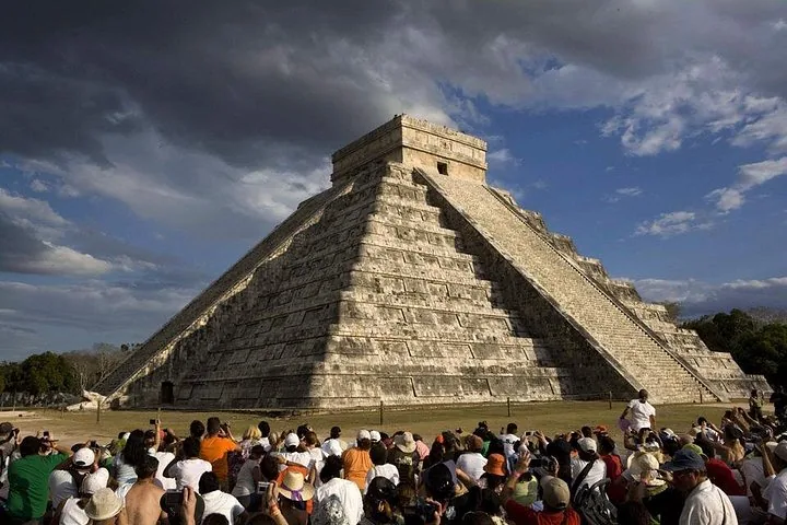Eine große Menschenmenge versammelt sich, um El Castillo in Chichén Itzá unter dramatischen Wolken zu sehen.