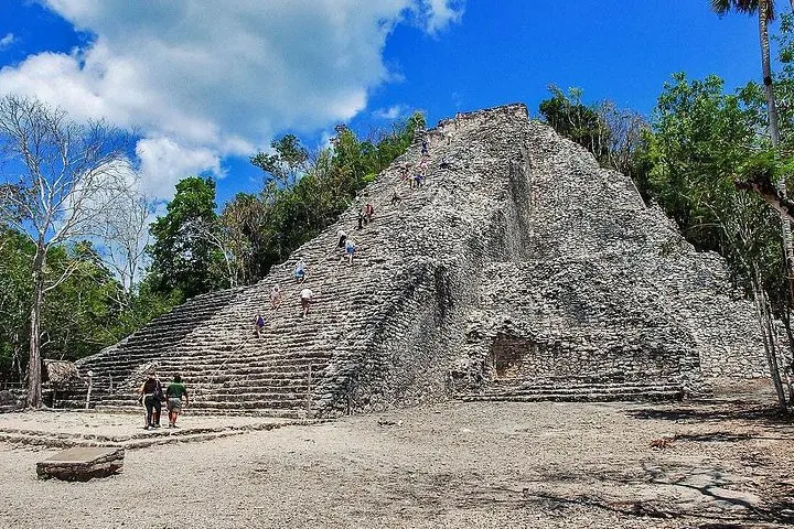 Menschen steigen die steilen Steinstufen einer hohen Maya-Pyramidenruine hinauf.